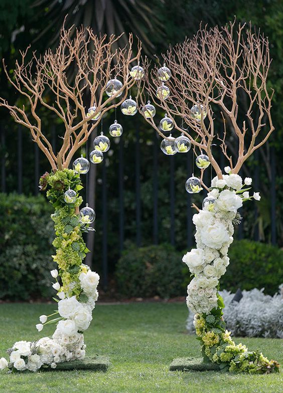 Branches create an archway with lovely white & green flower arrangements and hanging glass bubbles