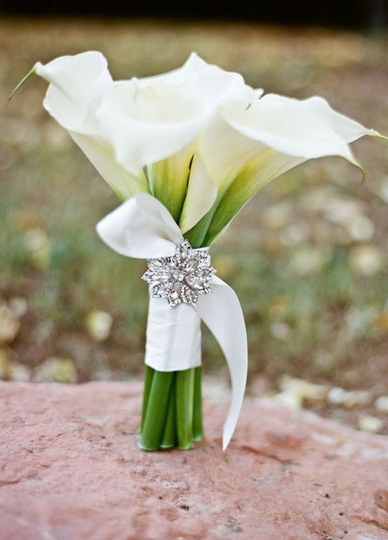 The brooch adds sparkle to this simple elegant white calla lily bouquet