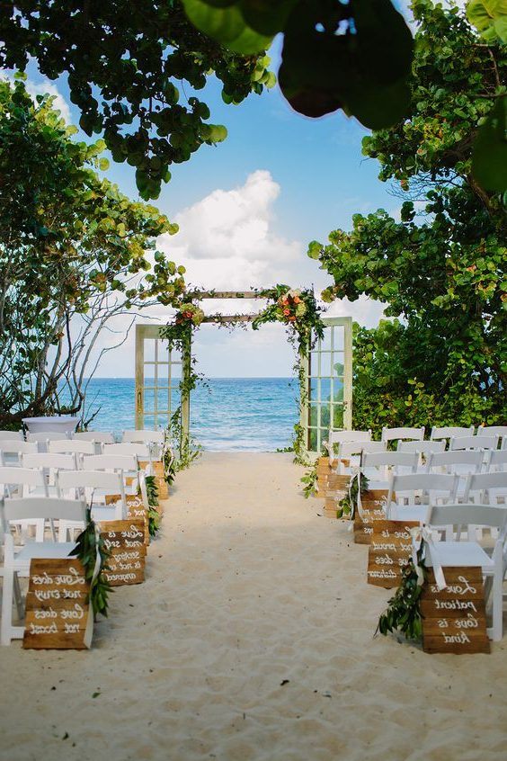 beach wedding ceremony with door arch and wooden aisle marker signs