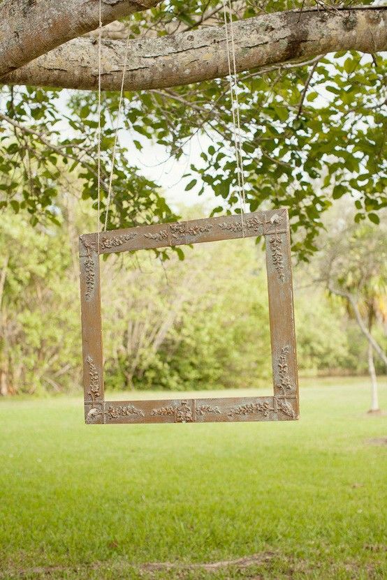 hang an empty picture frame from a tree branch at a rustic wedding reception