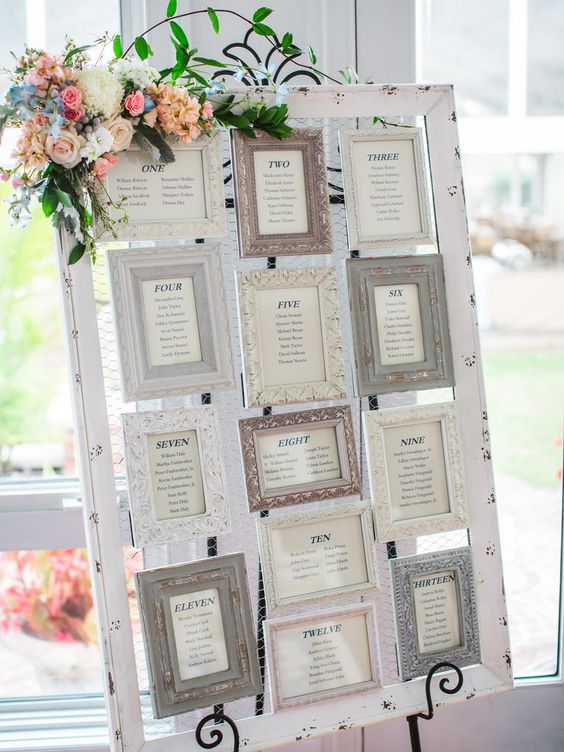 Seating chart at a wedding with chicken wire and frames mounted on it with table numbers
