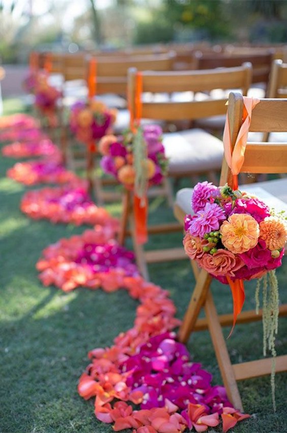 Bold orange and pink blooms make for a dramatic aisle