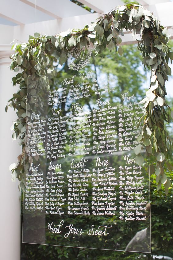 hand calligraphed lucite seating chart dripping with eucalyptus