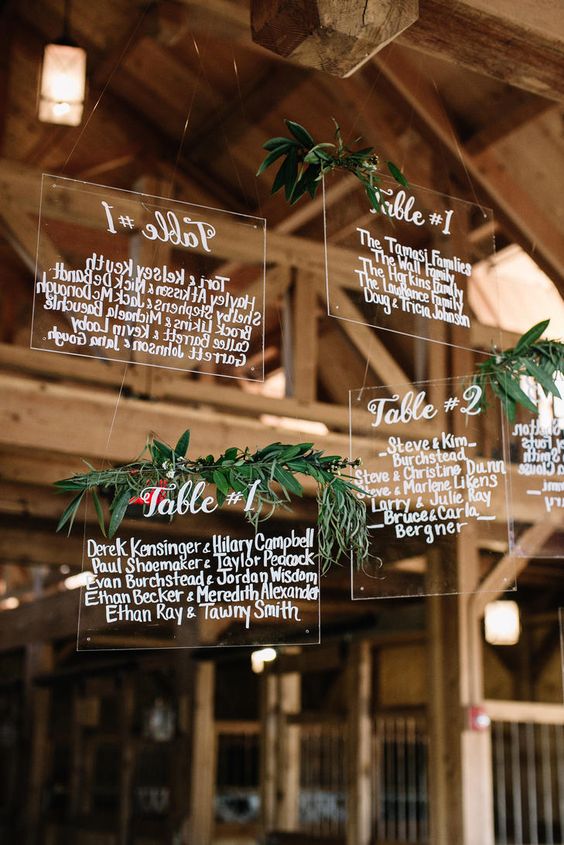 hand calligraphed lucite seating chart dripping with eucalyptus