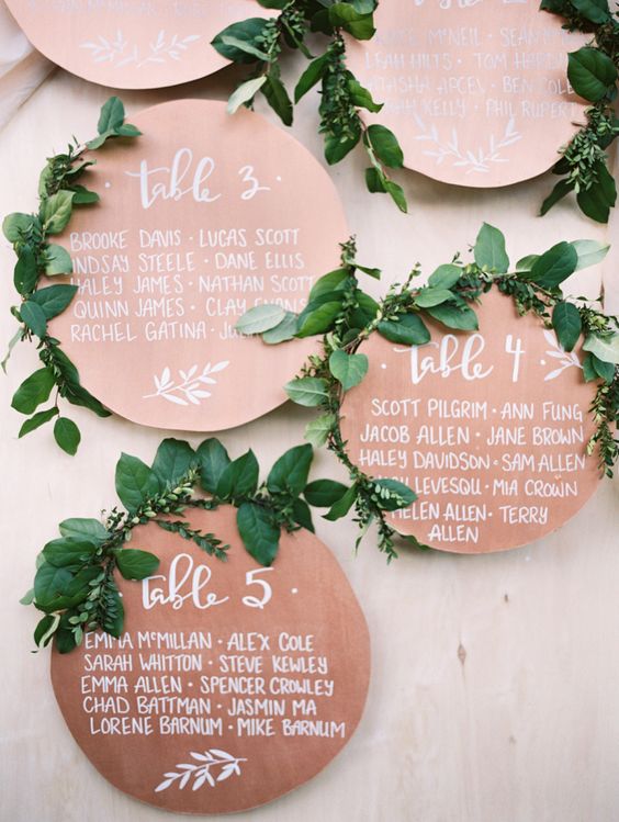 unique rose gold circular table cards topped with greenery