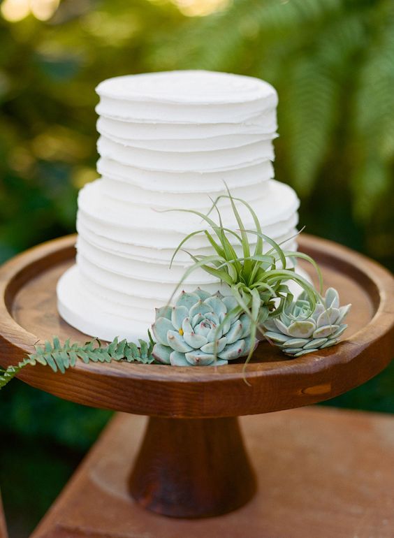 two tier white wedding cake on a wooden stand
