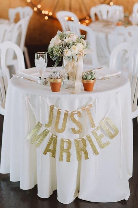 Dress up a simple white sweetheart table with a gold glittery banners and a bouquet as a centerpiece