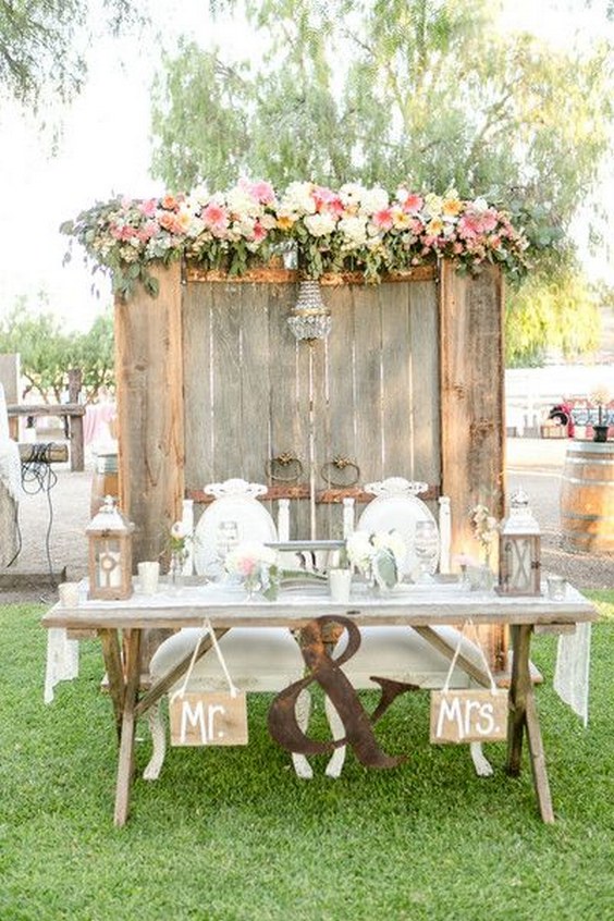 Rustic wedding idea for sweetheart table – wood barn door backdrop + pink flower garland via Leah Marie Photography