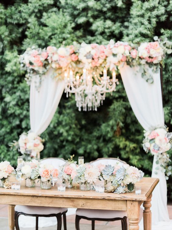 Wedding arch with fabric and chandelier. Sweetheart Table flowers