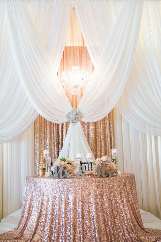 pipe and drape backdrop to a half moon sweetheart table in sequin rose gold
