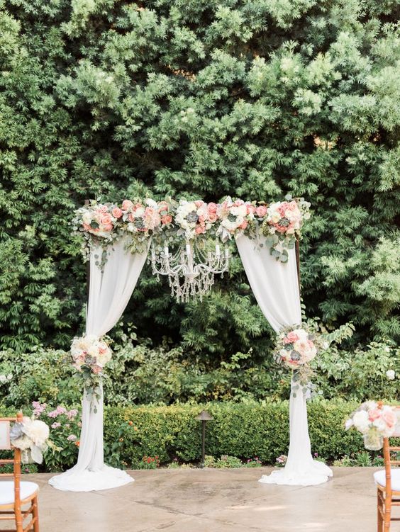 Wedding ceremony arch with draping fabric and chandelier