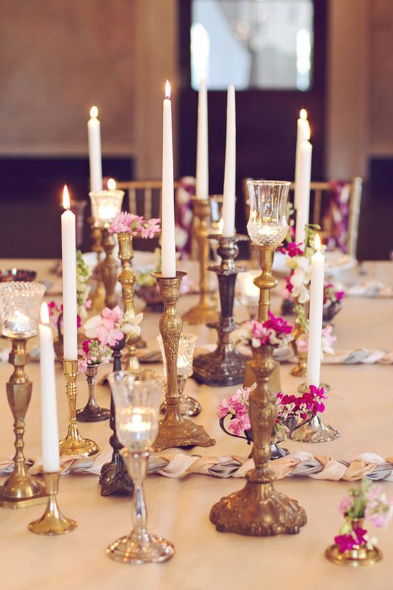 wedding centerpiece use glass bottle and accompany with varied candlesticks and votive candles