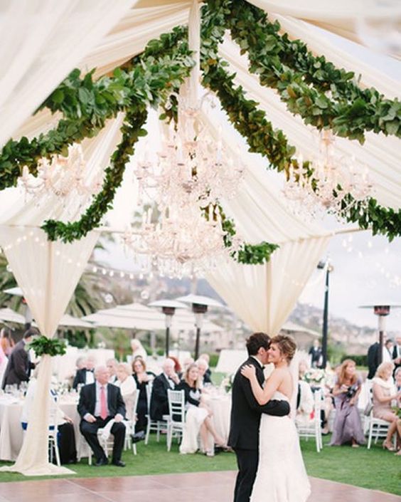 open tent with chandeliers and garlands of greenery
