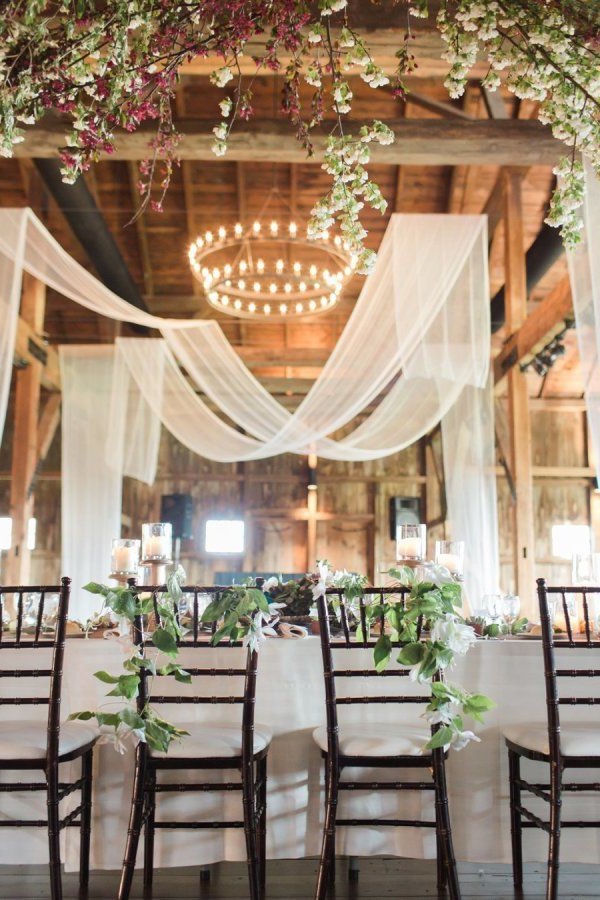 Rustic barn wedding reception space with draped fabric decor